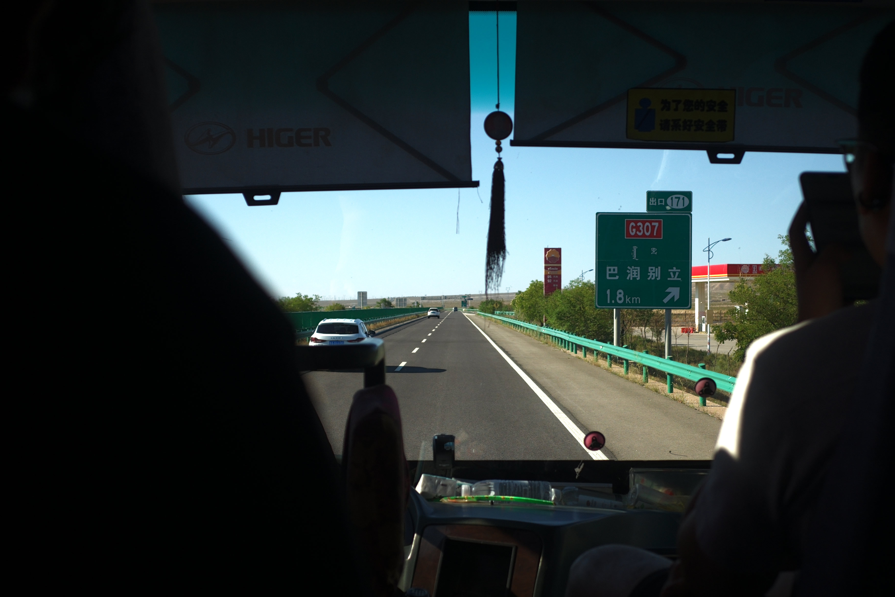 View through a coach windshield at a highway exit sign on the drive out to the desert